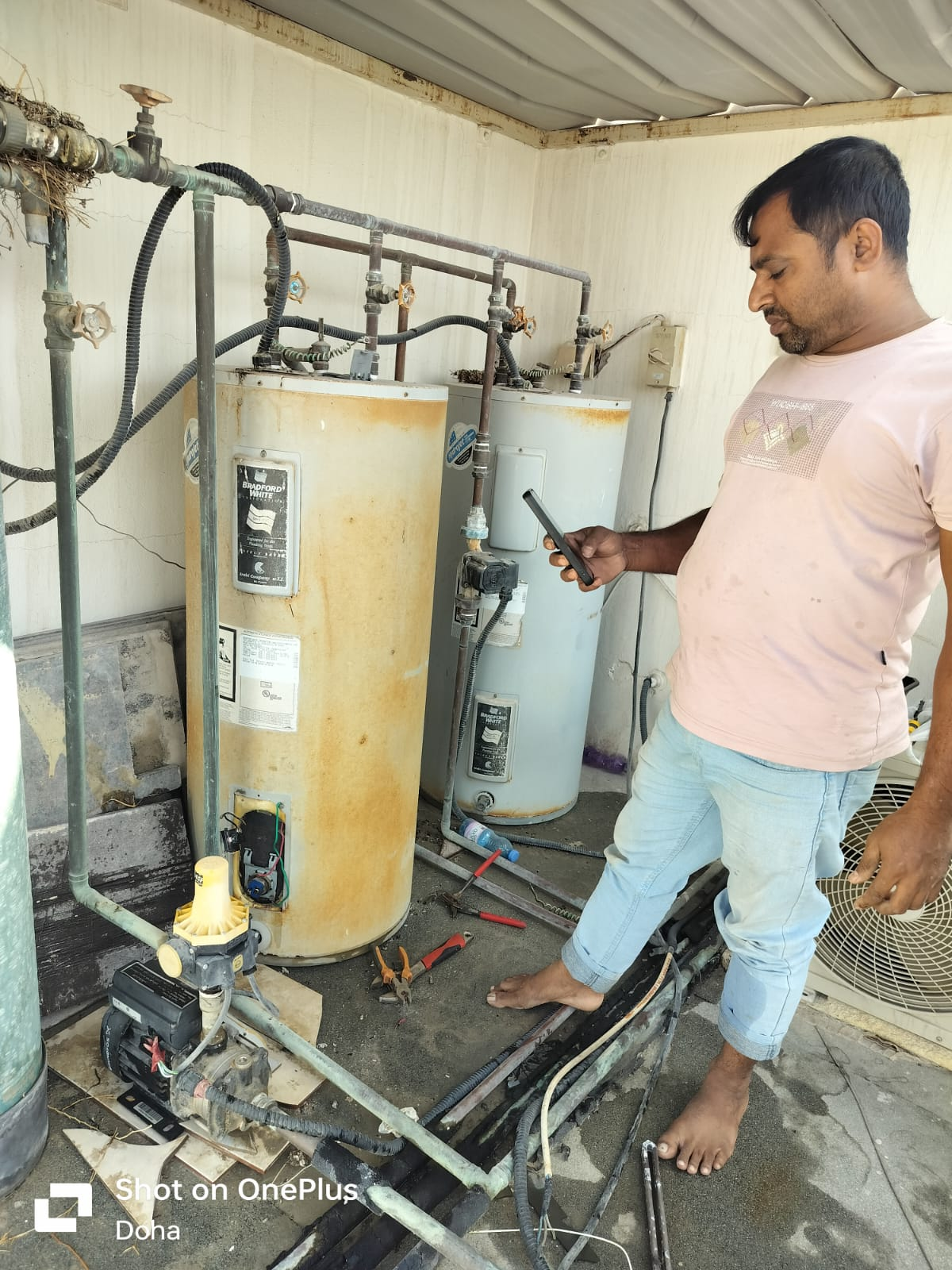 Professional electrical and plumbing technician working on water heater maintenance in Qatar